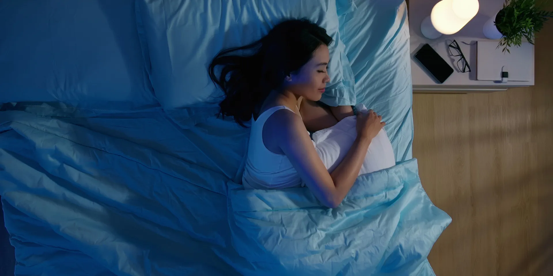 woman sleeping in a bed with table lamp on the night desk 